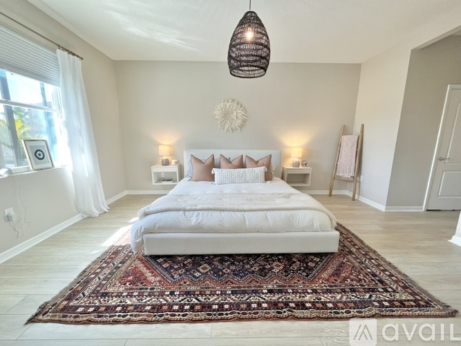 A bedroom with a large bed and a rug on the floor.