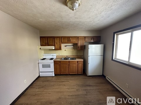 A kitchen with a white stove, sink, and refrigerator.