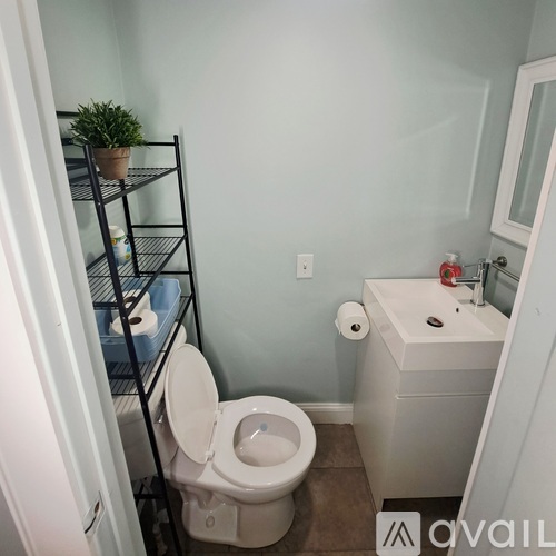 A white door is on the left side of a room with a grey wall and a light on the ceiling.