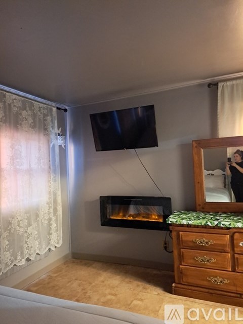 A room with a fireplace, a mirror, and a TV mounted on the wall.