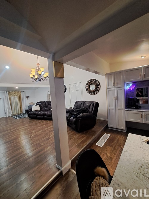 A living room with a black leather chair and a chandelier.