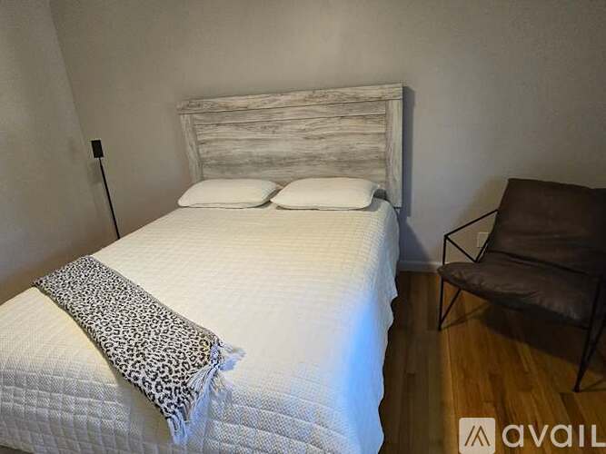 A bed with a white headboard and a leopard print throw on it.
