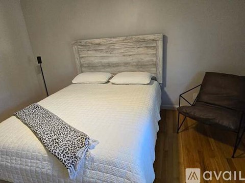 A bed with a white headboard and a leopard print throw on it.
