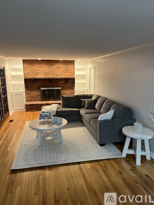 A living room with a grey couch, a white coffee table, and a brick fireplace.