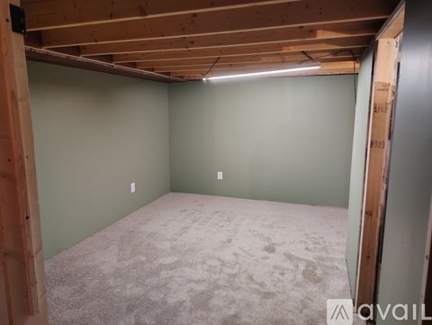 A room with a carpeted floor and wooden beams on the ceiling.