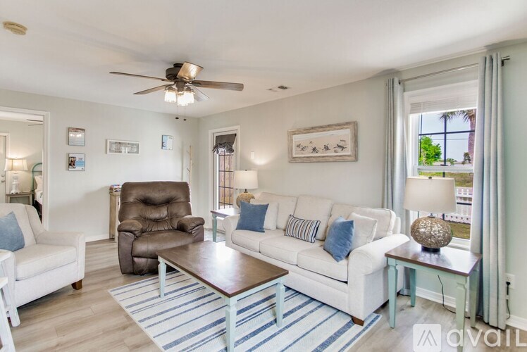 A living room with a white couch, brown chair, and a ceiling fan.