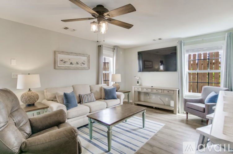 A living room with a brown leather chair and a white couch with blue pillows.
