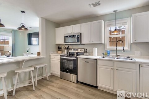 A kitchen with white cabinets and a wooden floor.