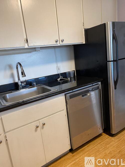 A kitchen with white cabinets and a black refrigerator.