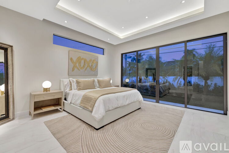 A bedroom with a large bed and a view of the outside through the glass doors.