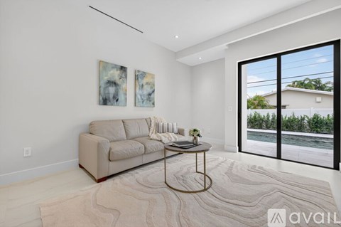 A living room with a beige couch, a coffee table, and two paintings on the wall.