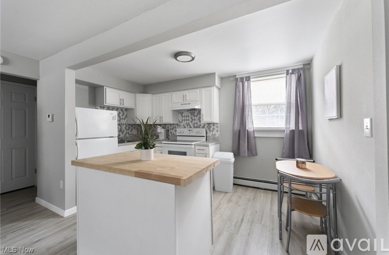 A kitchen with white cabinets and a wooden island.