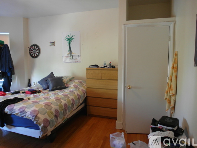 A bedroom with a bed, dresser, and a painting of a palm tree on the wall.