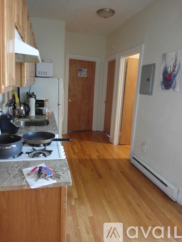 A kitchen with wooden floors and a white refrigerator.