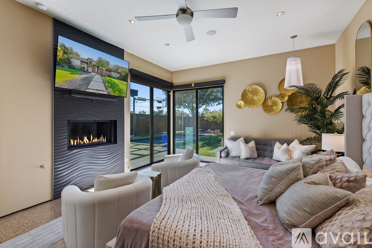A modern bedroom with a large bed and a flat screen TV mounted above the fireplace.