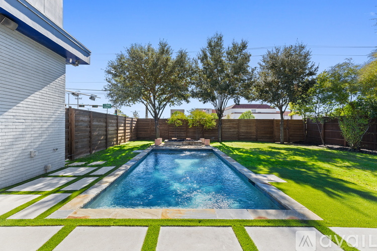 A pool surrounded by a green lawn and trees.