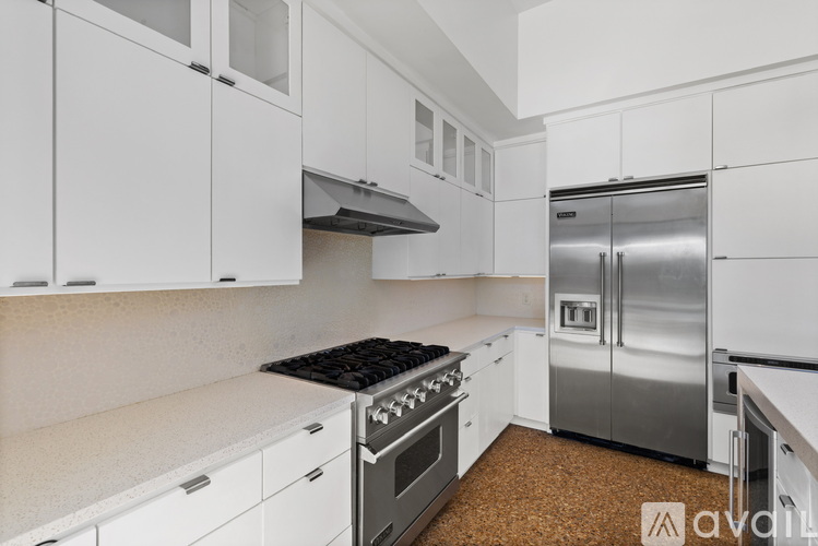A kitchen with white cabinets and a stainless steel refrigerator.