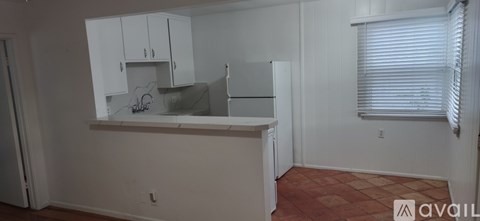 A kitchen with white cabinets and a refrigerator.