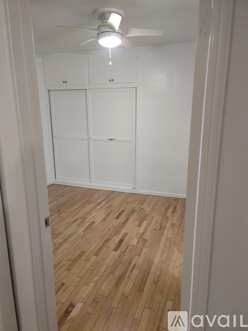 A room with a ceiling fan and wooden flooring.