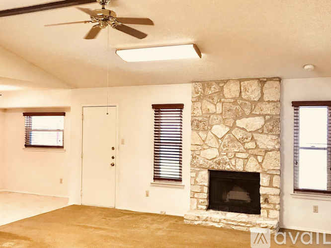 A living room with a stone fireplace and a fan.