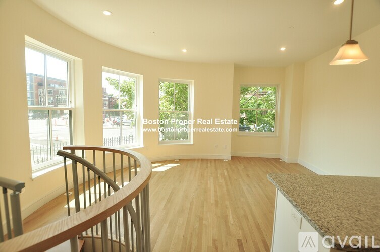 A spacious room with wooden flooring and a curved staircase.