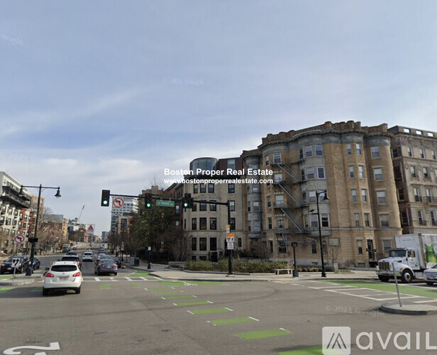 A street view of a city intersection with cars and buildings.
