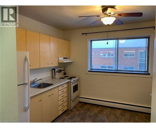 A kitchen with a refrigerator, sink, stove, and oven.