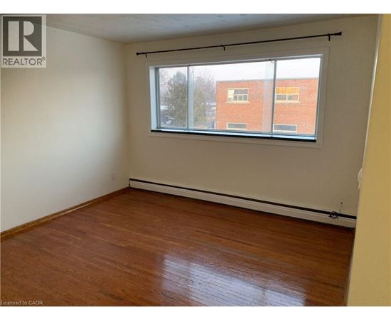 Empty room with a window and wooden flooring.