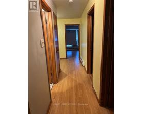 A hallway with wooden floors and doors on both sides.