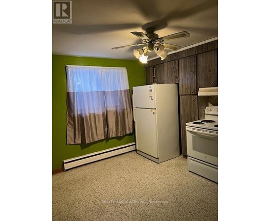 A kitchen with a white refrigerator, a white stove, and a ceiling fan.