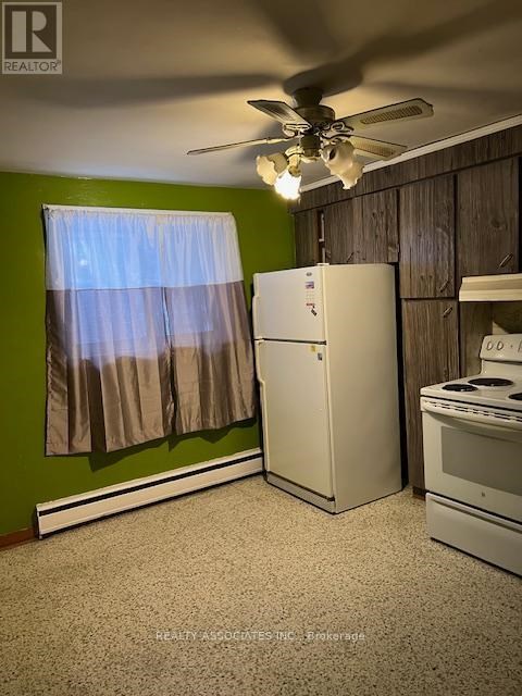 A kitchen with a white refrigerator, a white stove, and a ceiling fan.