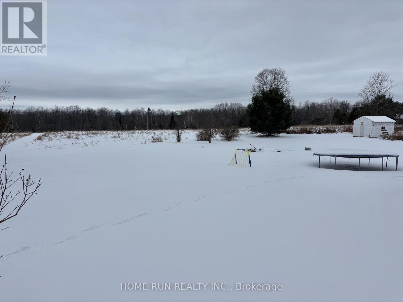A snowy field with a white barn and a yellow flag in the distance.