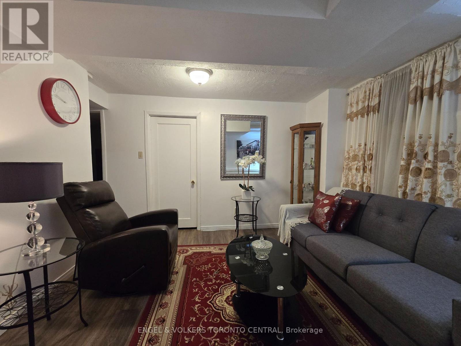 A living room with a grey couch, a black chair, and a red rug.