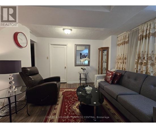 A living room with a grey couch, a black chair, and a red rug.