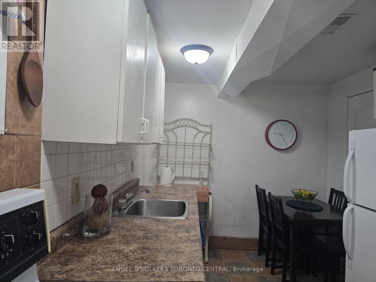 A kitchen with a sink, a table and chairs, and a clock on the wall.