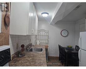 A kitchen with a sink, a table and chairs, and a clock on the wall.