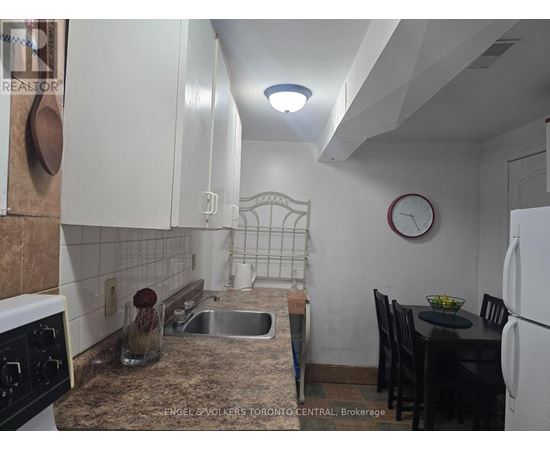 A kitchen with a sink, a table and chairs, and a clock on the wall.