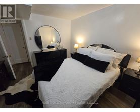 A bedroom with a large bed and a mirror on the dresser.