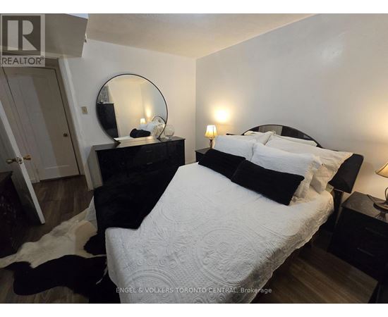 A bedroom with a large bed and a mirror on the dresser.
