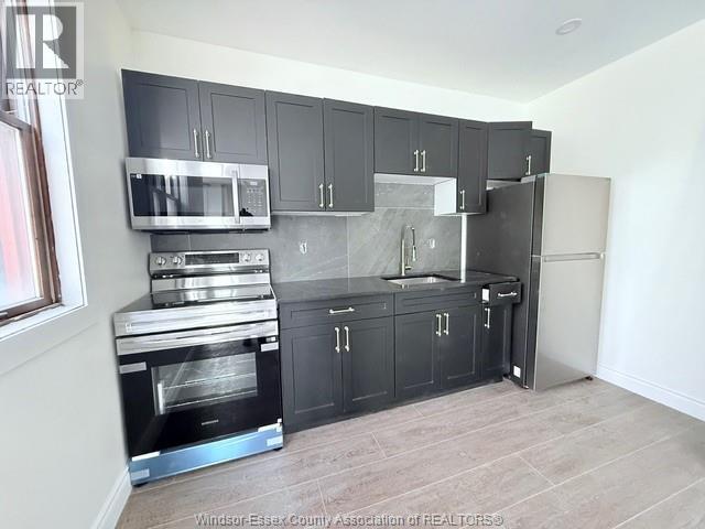 A kitchen with black cabinets and stainless steel appliances.