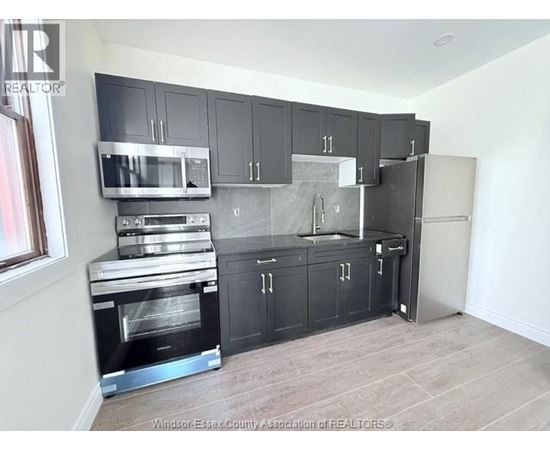 A kitchen with black cabinets and stainless steel appliances.
