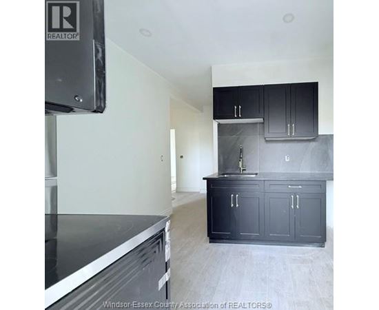 A kitchen with black cabinets and a stainless steel dishwasher.