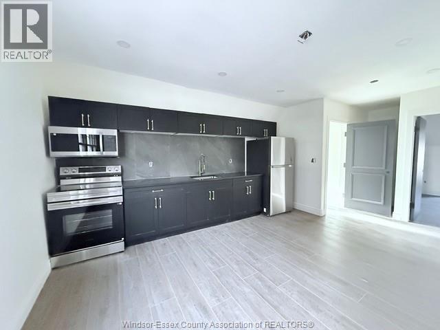 A kitchen with black cabinets and stainless steel appliances.