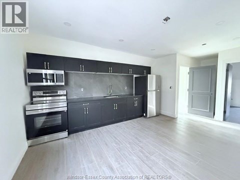 A kitchen with black cabinets and stainless steel appliances.