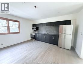 A kitchen with black cabinets and a stainless steel refrigerator.