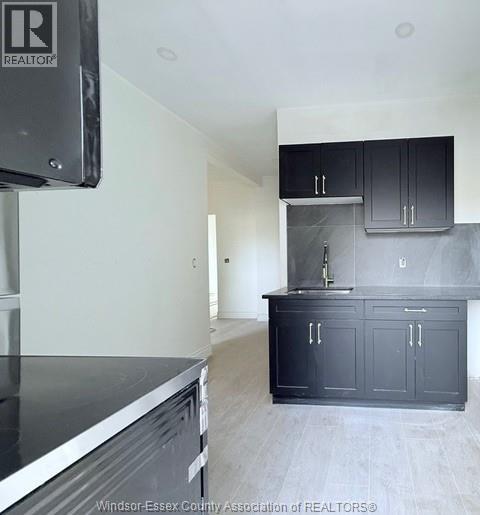 A kitchen with black cabinets and a stainless steel dishwasher.