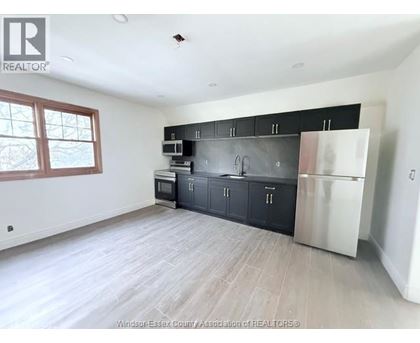 A kitchen with black cabinets and a stainless steel refrigerator.