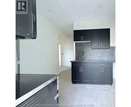 A kitchen with black cabinets and a stainless steel dishwasher.