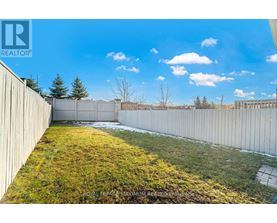 A backyard with a fence and grass.