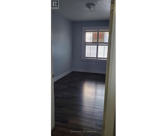 A room with a window and wooden flooring.